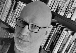 Imagen del profesor en blanco y negro sobre un fondo de estantería con libros